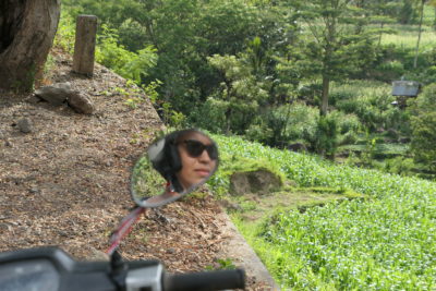 Reflet d’une femme avec des lunettes de soleil dans le rétroviseur d’un scooter
