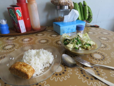 Repas composé de tempeh frit et de légumes en sauce dans un warung